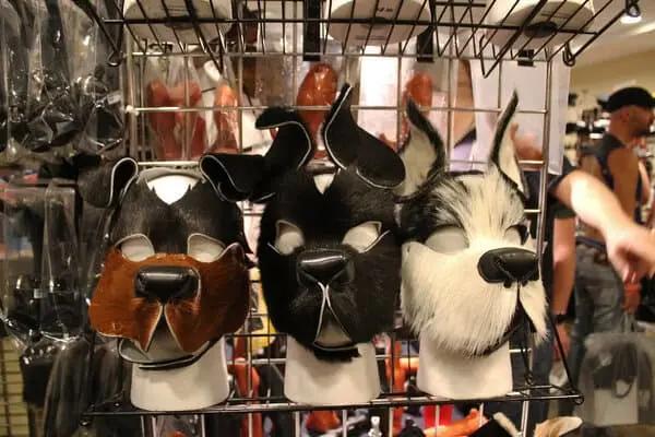 Drei Tiermasken in Form von Hunden, gefertigt aus Kunstleder, auf einem Ständer ausgestellt.